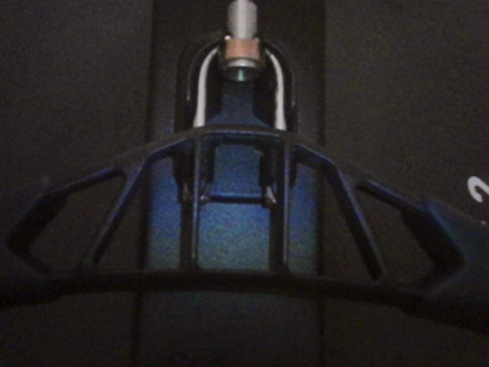Close-up of a rowing machine handle in low light, with a subtle blue reflection on the metal surface.