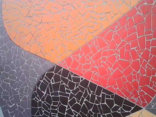 Close-up of a colourful mosaic wall with broken tile fragments in orange, red, dark grey and light grey, arranged in bold sweeping geometric sections – shot with a Kodak camera in fading natural light.