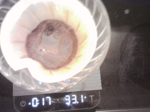 Bloom phase of a pour-over coffee brew in a paper filter on a glass dripper placed on a digital scale.