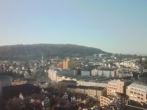 Soft, hazy morning view over Zürich Oerlikon with residential buildings in the foreground and the Irchel hill in the background