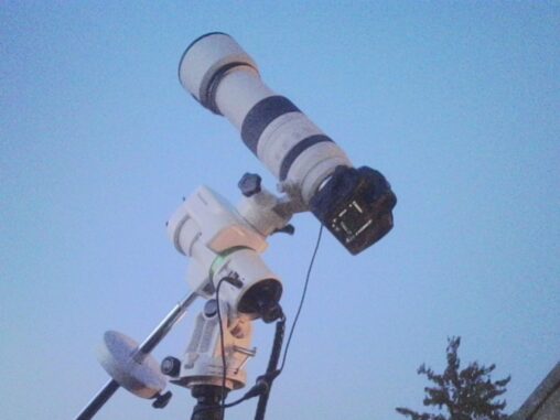 Portable astrophotography setup with a telescope and camera mounted on a compact tripod, pointed at a clear evening sky.