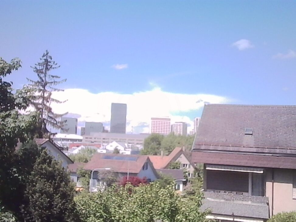 Zurich Nord skyline rising above residential rooftops under a bright late-spring sky