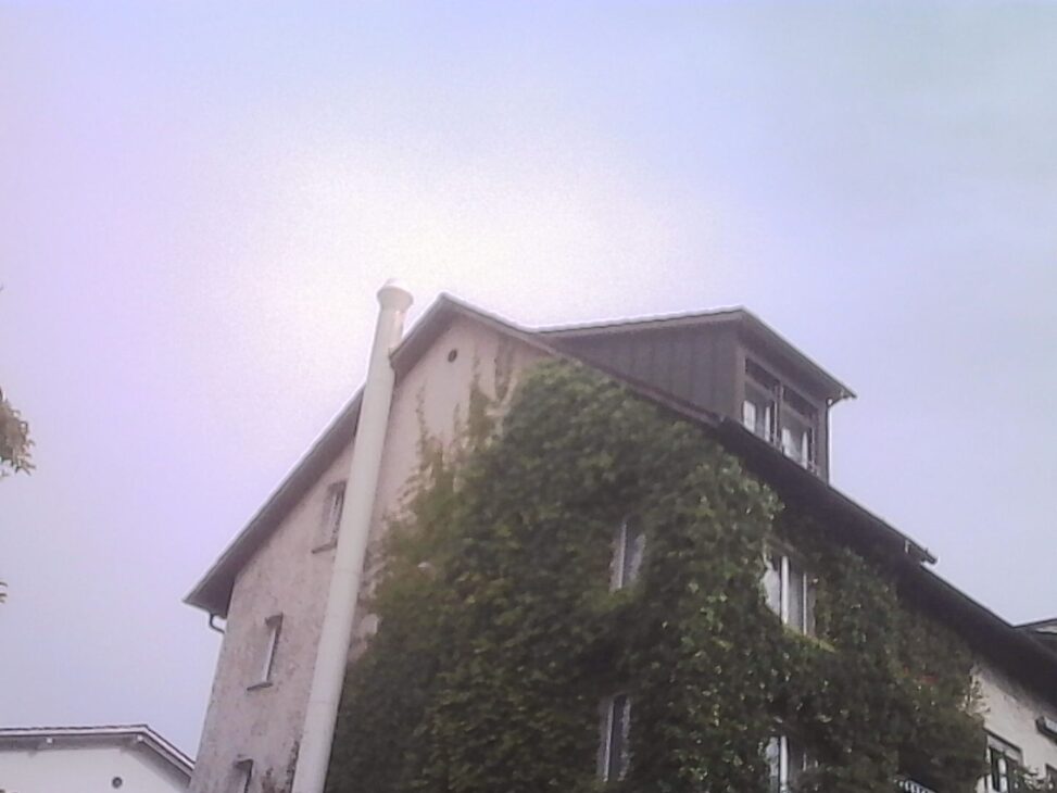 Ivy-covered residential building beneath a hazy bright sky during a quiet neighborhood walk
